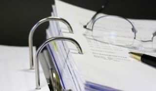 An open notebook with eyeglasses and pen